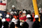 Le mineur Florencio Avalos (c, chemise beige) serre le président chilien Sebastian Pinera dans ses bras après être sorti de la capsule Fenix qui l'a ramené à la surface, le 12 octobre 2020 à la mine de San José, dans le désert d'Atacama