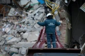 Un secouriste guide l'opérateur d'une grue qui enlève les gravats de l'immeuble partiellement effondré, le 2 janvier 2019