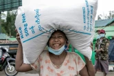 Une femme porte un sac de riz distribué par le PAM à Rangoun le 21 mai 2021