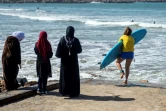 Une surfeuse en tenue de bain entre dans l'eau sur une plage de Rabat, le 1er avril 2018