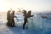 Des villageois en Iakoutie (nord-est de la Sibérie) extraient un bloc de glace qui les approvisionnera en eau douce pour l'hiver, le 27 novembre 2018 à Oï en Russie