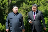 Photo fournie le 9 mai 2018 par l'agence nord-coréenne Kcna du leader nord-coréen Kim Jong Un (g) et du président chinois Xi Jinping, lors d'une rencontre à Dalian le 8 mai 2018, en Chine
