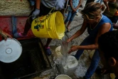 Des habitants du quartier de Petare remplissent des bidons d'eau pour l'utiliser dans leurs toilettes, le 1er avril 2019 à Caracas, au Venezuela