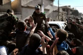 Un membre des forces de sécurité irakiennes distribue de la nourriture à des civils le 10 mars 2017 à Mossoul