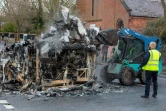 Des employés du conseil municipal de Belfast  nettoient les restes d'un bus brûlé à  Shankill Road le 8 avril 2021