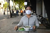 Une serveuse apporte un bol de soupe aux nouilles à un client dans une rue de Ho Chi Minh-Ville, le 8 septembre 2020 au Vietnam