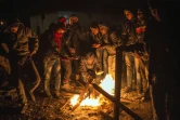 Migrants et réfugiés se réchauffent autour d'un feu de bois le 23 octobre 2015 à Gevgelija à la frontière entre la Macédoine et la Grèce