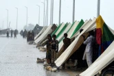 Des déplacés ayant fui leurs maisons inondées devant des tentes temporaires installées le long d'une route lors de fortes pluies de mousson à Sukkur, dans la province de Sindh, au Pakistan, le 27 août 2022