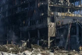 Des pompiers au travail sur la carcasse encore fumante du centre commercial Retroville, à Kiev le 21 mars 2022