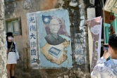 Une touriste se fait photographier près d'une fresque murale de l'ancien président taïwanais Tchang Kaï-chek, le 11 août 2022 aux îles de Kinmen, à Taïwan