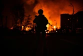 Un membre des forces spéciales de la police ukrainienne observe une station-service en feu, après un bombardement russe, à Kharkiv, le 30 mars 2022.