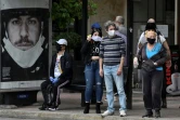 Des passagers, le visage couvert d'un masque de protection contre le coronavirus, attendent leur bus, au premier jour du déconfinement à Athènes le 4 mai 2020