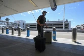 Un homme portant un masque pousse ses bagages à l'aéroport international de Los Angeles le 12 août 2020 pendant l'épidémie de coronavirus