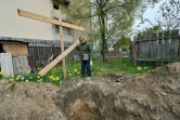 Une femme se tient devant l'endroit où a été exhumé le corps de son défunt mari, devant leur maison à Boutcha, près de Kiev, le 27 avril 2022