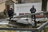 Des policiers devant les dégâts d'un bombardement à Kiev, le 24 février 2022 en Ukraine