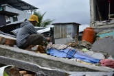 Un homme près du corps d'une victime dans les décombres, à Mamuju, sur l'île des Célèbes en Indonésie, le 15 janvier 2021