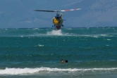 Un hélicoptère de lutte contre les incendies fait le plein d'eau à proximité de baigneurs, le 27 juillet 2023 sur l'île de Corfu, en Grèce