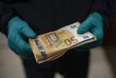 Un policier catalan examine une liasse de billets saisie pendant un raid contre une "ferme" illégale de cannabis dans la banlieue de Barcelone, le 6 octobre 2020