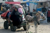 Une Palestinienne et une petite fille sont montées sur une charrette tirée par un âne suite à l'ordre d'évacuation de l'armée israélienne pour certaines parties de Khan Younès, dans le sud de la bande de Gaza, le 23 juillet 2024