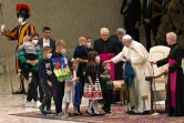 Le pape François, un drapeau ukrainien venant la ville de Boutcha à la main, rencontre de jeunes réfugiés ukrainiens le 6 avril 2022 au Vatican