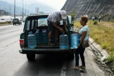 Des habitants du quartier Petare chargent des bidons d'eau dans une camionnette, le 1er avril 2019 à Caracas, au Venezuela