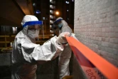 Policiers à Hong Kong en tenue de protection installent un cordon autour d'un bâtiment le 11 février 2020, après que deux personnes y ont contracté le nouveau coronavirus

 