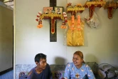 Pirun Kla-Talay et son épouse Janjira Khampradit assis dans leur maison sous les portraits des parents de Pirun, morts dans le tsunami de 2004, le 19 novembre 2024 dans la province de Phang Nga, le 19 novembre 2024 en Thaïlande