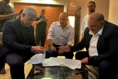Une photo fournie par le parti arabe israélien Raam montre le chef du parti Mansour Abbas (D) signer l&rsquo;accord de coalition avec le chef de l&rsquo;opposition Yaïr Lapid (G) et le chef de la droite radicale Naftali Bennett (centre) à Ramat Gan, près de Tel-Aviv, le 2 juin 2021 