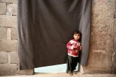 Un enfant syrien devant le rideau qui fait office de porte d'entrée aux chambres de déplacés syriens qui ont trouvé refuge dans une cave dans la ville d'Al-Bab (nord syrien), le 7 décembre 2018