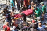 Des Palestiniens et des secouristes transportent le corps d'un Palestinien tué lors d'un bombardement israélien qui a touché une école abritant des déplacés à Gaza-Ville, le 4 août 2024
