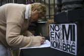 Une femme paraphe un document renonçant à son baptême à côté d'une pancarte disant "Pas en mon nom. Apostasie collective", devant le siège de la conférence épiscopale argentine, le 24 août 2018