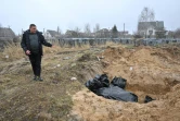Un homme se tient près d'une fosse commune à Boutcha, près de Kiev, le 3 avril 2022