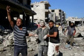 Accompagné de deux hommes, un Syrien sort des décombres d'un immeuble visé par un bombardement, à Maaret al-Noomane, dans le nord-ouest de la Syrie, le 22 juillet 2019
