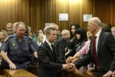 Oscar Pistorius serre la main de son oncle Arnold Pistorius avant d'être emmené en prison à l'issue de son procès le 21 octobre 2014 à Pretoria