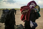 Des femmes croulant sous de lourds sacs à dos et baluchons fuient le dernier réduit du groupe Etat islamique (EI) à Baghouz dans l'est de la Syrie, le 6 mars 2019