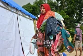 Une femme porte des vêtements donnés par un centre d'aide dans le village de Citangkil à Sumur, le 25 décembre 2018, trois jours après le tsunami qui a frappé l'Indonésie