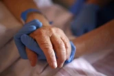 Un personnel soignant tient la main d'un patient en soins palliatifs, à l'hôpital Eugénie d'Ajaccio, le 23 avril 2020