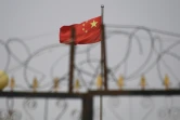 Le drapeau chinois flotte derrière des barbelés dans un complexe immobilier du Xinjiang, en Chine, en juin 2019 
