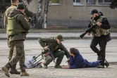 Des membres des forces ukrainiennes contrôlent un passant après un bombardement russe à Kharkiv, le 31 mars 2022. 