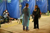 Des femmes et leurs enfants attendent à l'extérieur du centre médical Caritas où elles s'apprêtent à passer la nuit, le 16 février 2022 à Hong Kong