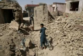 Des Afghans marchent le 16 août 2018 près de maisons détruites à la suite d'une attaque des talibans à Ghazni