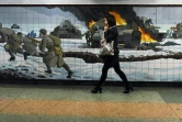 Une femme passe devant une mosaïque murale représentant une scène de bataille de la Deuxième guerre mondiale dans la ville russe de Rostov-sur-le-Don frontalière de l'Ukraine le 22 février 2022.