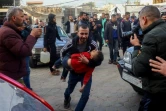 Un Palestinien porte un enfant blessé dans un hôpital après une meurtrière frappe israélienne sur Deir el-Balah, dans le centre de la Bande de Gaza, le 14 janvier 2025