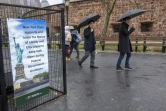 Des passants devant une pancarte expliquant que New York paie pour garder la Statue de la Liberté ouverte aux touristes, alors que les Etats-Unis entrent dans leur troisième semaine de "Shutdown", le 5 janvier 2019 à New York