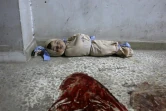 Le corps d'un enfant syrien enveloppé dans une couverture et placé à même le sol dans une clinique de fortune dans la localité de Douma, dans le fief rebelle de la Ghouta orientale, cible de bombardements intensifs du régime, le 22 février 2018 
 
