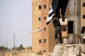 Un membre des forces démocratiques syriennes enlève un drapeau du groupe d'État islamique dans la ville de Tabqa, à environ 55 kilomètres (35 milles) à l'ouest de Raqa, 30 avril 2017