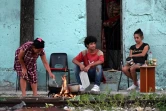 Des habitants cuisinent sur un feu de bois devant leur maison à La Havane pendant une panne de courant à Cuba, le 15mars 2025