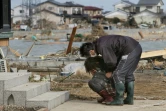 Une habitante de Watari, dans le nord-est du Japon, s'effondre en larmes devant sa maison détruite par le séisme et le tsunami, le 14 mars 2011