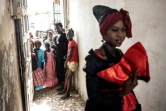 Des jeunes filles regardent un mannequin travaillant avec la créatrice de mode, Ndeye Diop Guisse, en tenue traditionnelle des Signares à Saint Louis, le 10 août 2021