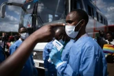 Un membre du Centre biomédical du Rwanda prend la température des passagers à un gare routière à Kigali, le 22 mars 2020